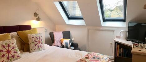 A bedroom with a bed, a chair, a television, and a bookshelf.