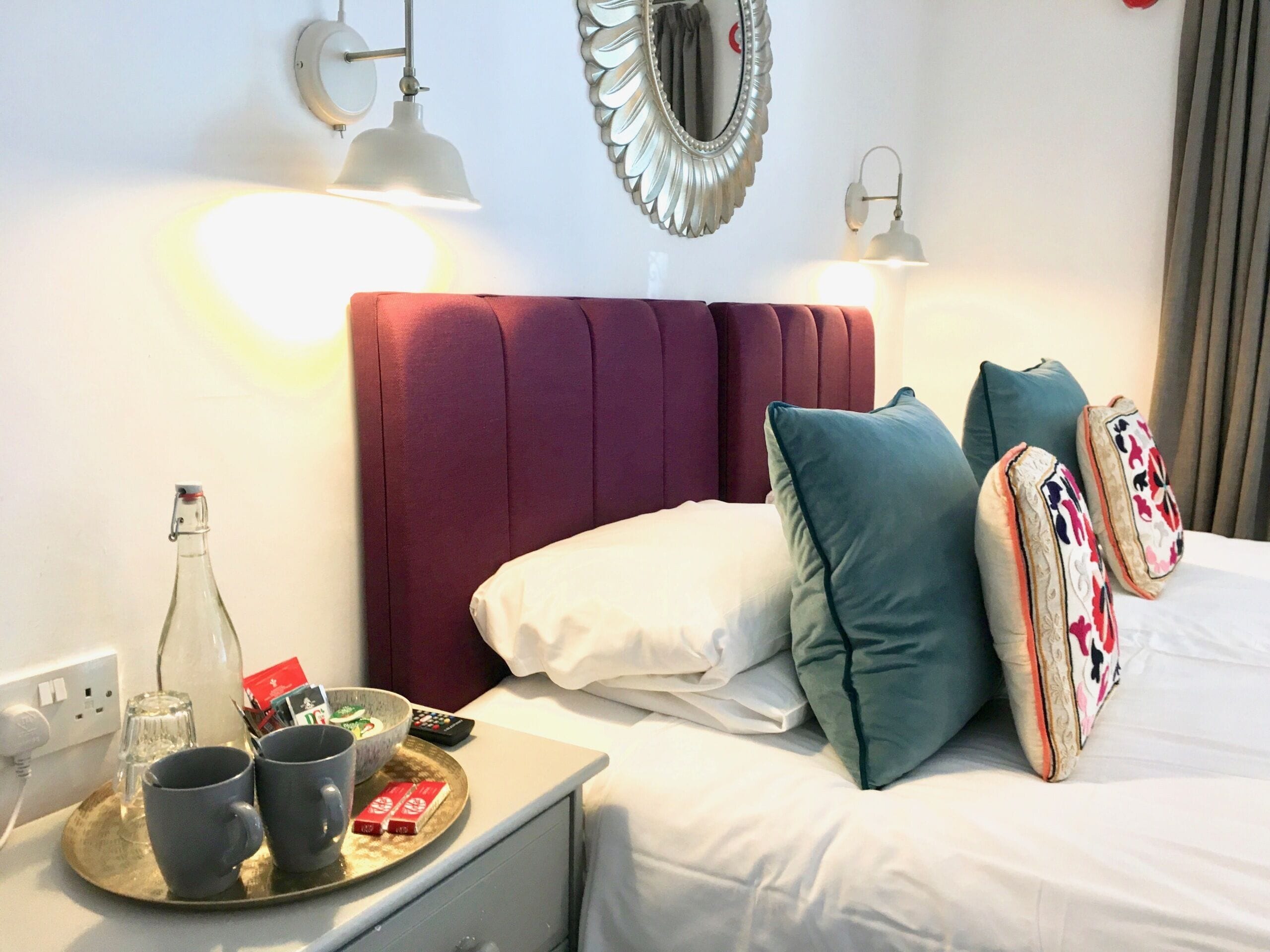 Una habitación de hotel con cama, mesita de noche y otra mesita auxiliar.