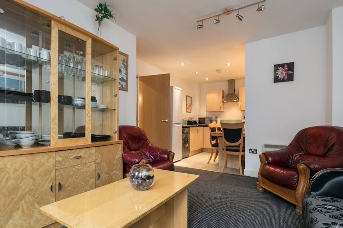 A modern living room with a wooden cabinet, leather chairs, and a dining table.