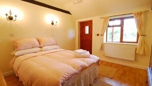 A bedroom with a bed, a window with curtains, a radiator, and a wall-mounted light fixture. - New Inn (Ilminster)