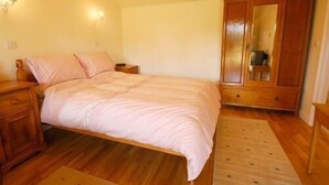 A bedroom with a bed, wooden nightstands, a wardrobe, and a mirror. - New Inn (Ilminster)