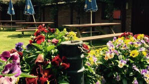A garden area with picnic tables and umbrellas, surrounded by colorful flowers. - New Inn (Ilminster)