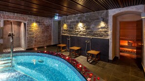 Un área de spa con piscina, bancos de madera y pared de piedra.