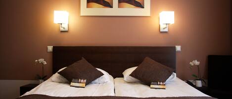 A hotel room with a large bed, two wall-mounted lamps, and a framed artwork above the bed.
