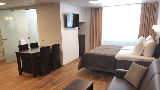 Una habitación de hotel con cama, sofá, escritorio y televisor.