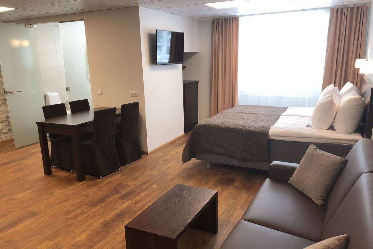 Ett hotellrum med en säng, en soffa, ett skrivbord och en tv.