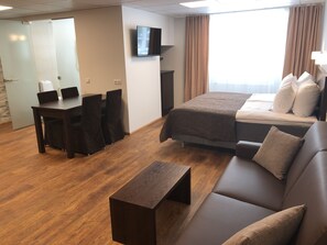 Una habitación de hotel con cama, sofá, escritorio y televisor.