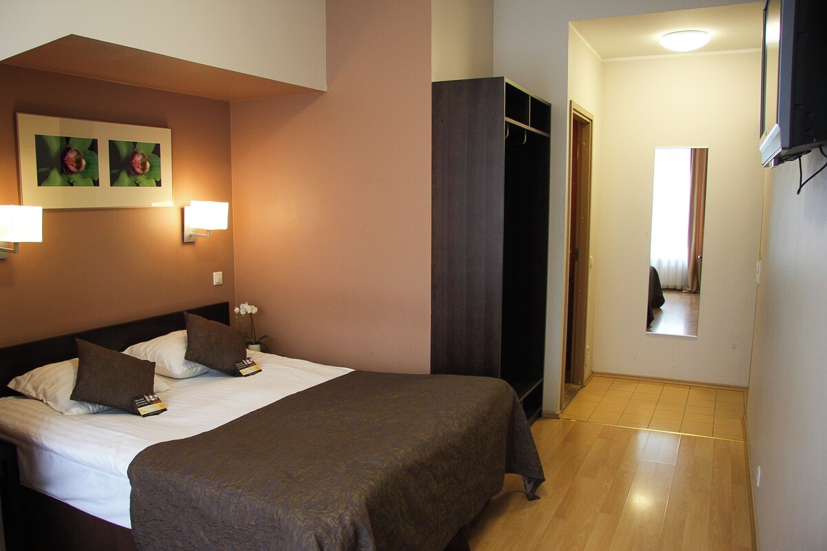 A hotel room with two beds, a wardrobe, a mirror, and a TV.