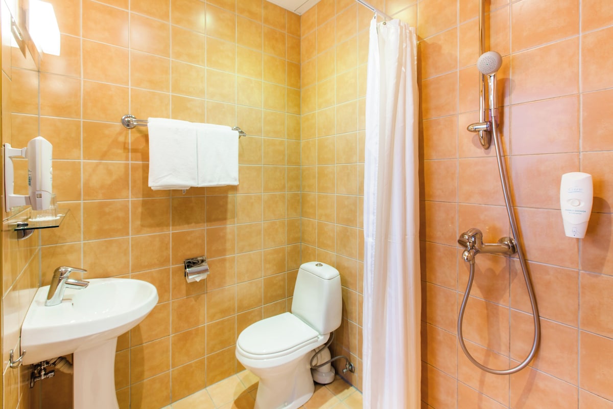 A bathroom with a sink, toilet, shower, and a towel rack.