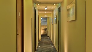 Pasillo de hotel con pisos alfombrados, puertas y un cartel que indica las habitaciones 15 a 17.
