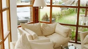 A room with a large window, a beige sofa, and a small table. - San Remo Viking Hotel (Pinamar)