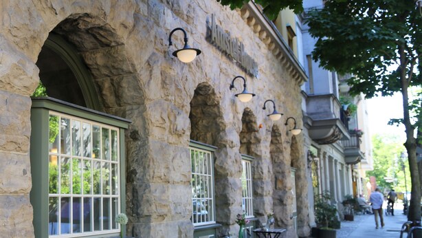 Un edificio de piedra con ventanas de arco y asientos al aire libre.