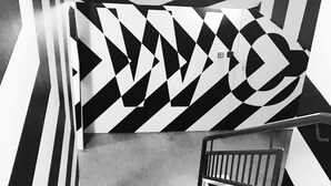 Una escalera con un muro de diseño geométrico y barandilla de metal.