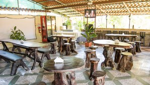 A restaurant with rustic wooden tables and benches, a tiled floor, and a television screen. - Lavas del Arenal (Peñas Blancas)