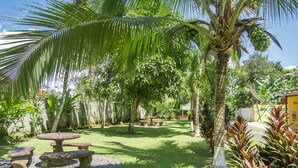 A garden with a stone table and benches, surrounded by palm trees and tropical plants. - Lavas del Arenal (Peñas Blancas)