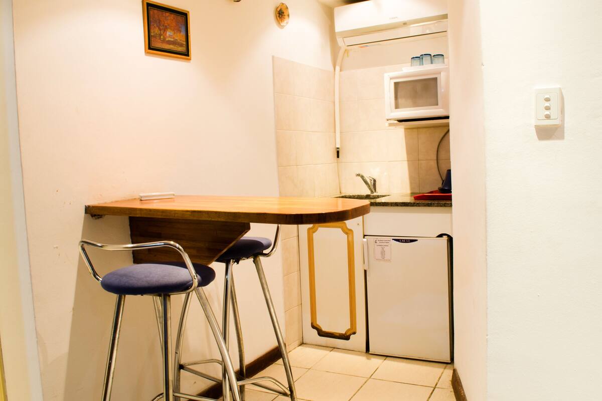 A small kitchen with a wooden table and two bar stools.