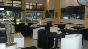 A hotel lobby with multiple seating areas, a reception desk, and a large window overlooking the street.