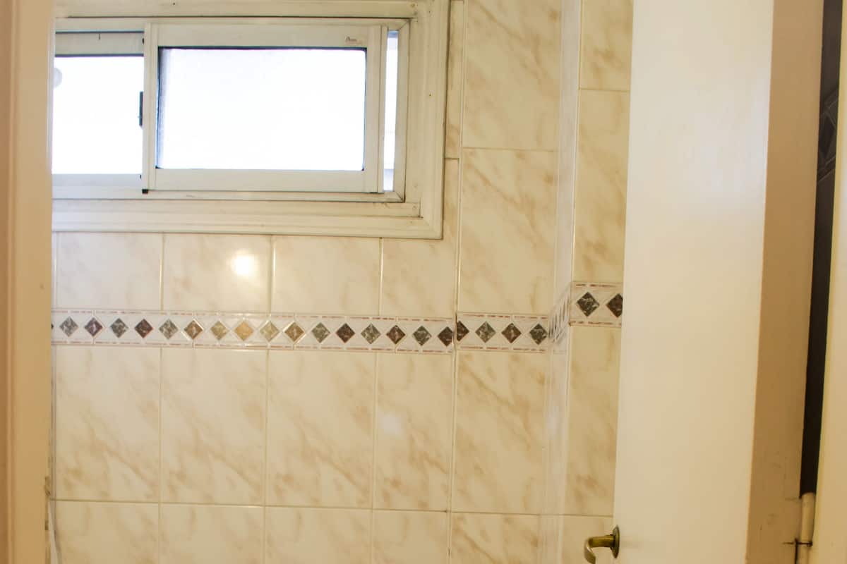 A small bathroom with a toilet, bidet, and a window above the toilet.