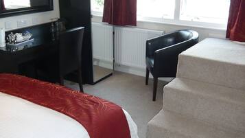 Habitación de hotel con cama, escritorio, silla y vistas al exterior por la ventana.