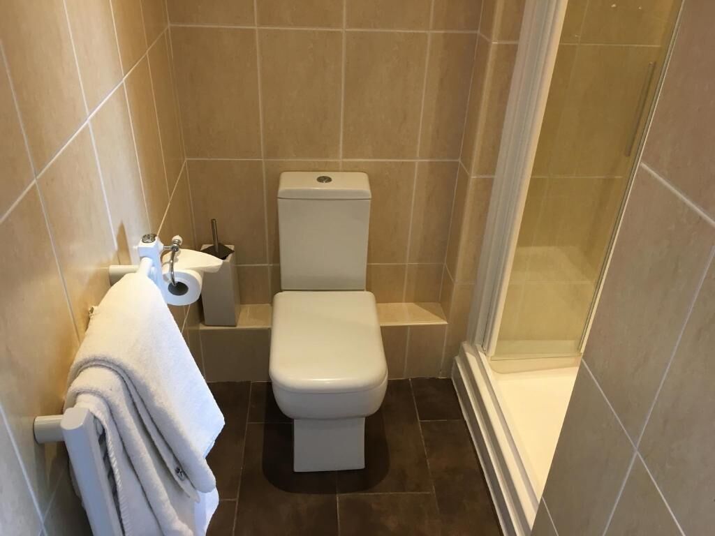 Un baño pequeño y moderno con inodoro, lavamanos y zona de ducha.