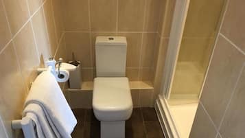Un baño pequeño y moderno con inodoro, lavamanos y zona de ducha.