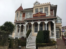 Un hotel de estilo victoriano con un letrero llamativo, varios balcones y una entrada imponente.
