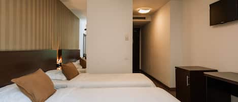 Habitación de hotel con dos camas, un escritorio, un televisor y una puerta que da a otra habitación.