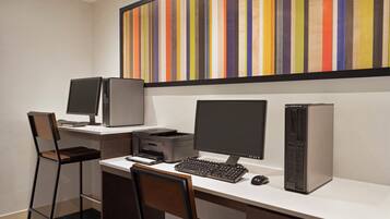 A workspace with two monitors, a desktop computer, a printer, and a keyboard.
