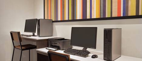 A workspace with two monitors, a desktop computer, a printer, and a keyboard.
