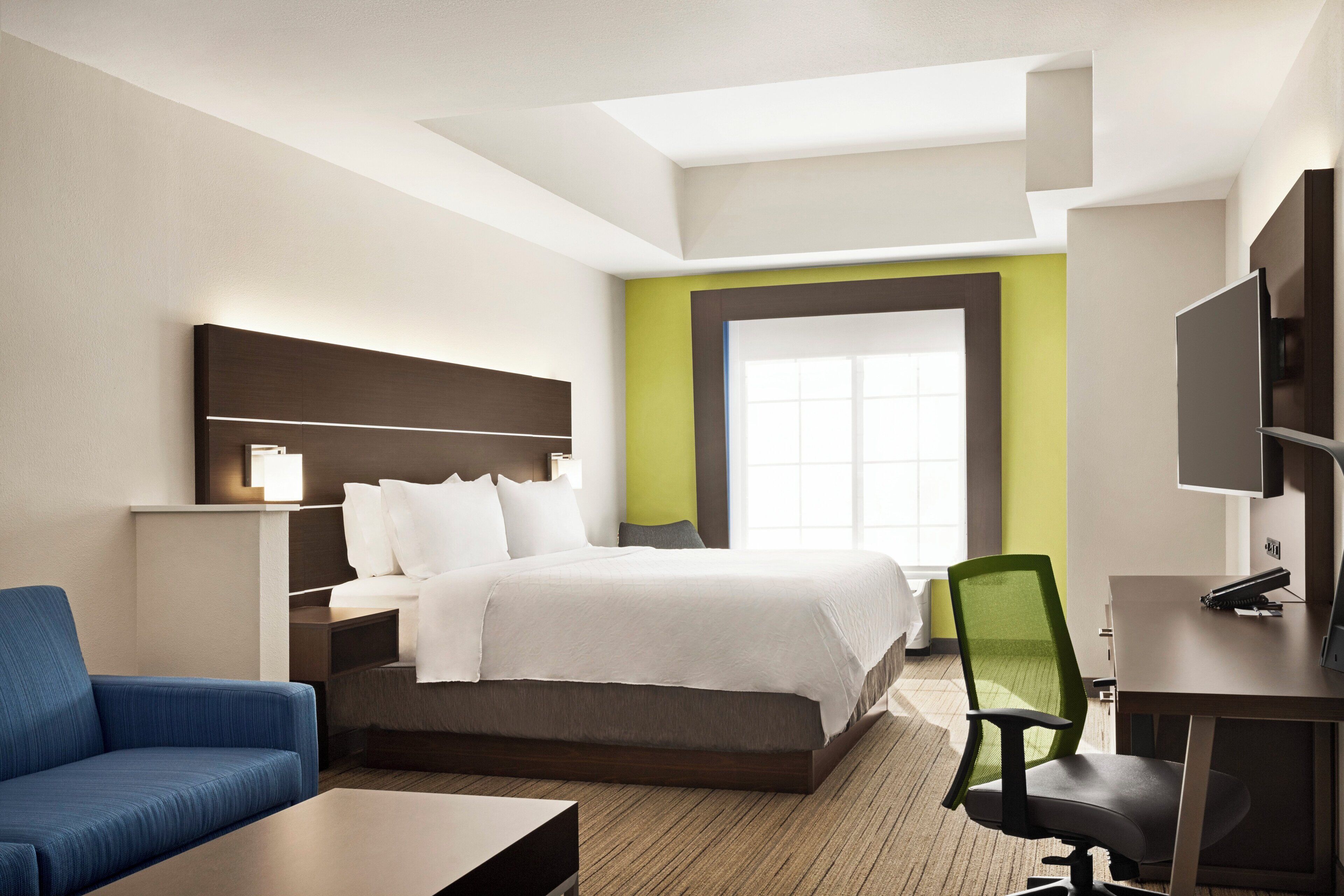 Ein Hotelzimmer mit einem Bett, einem Schreibtisch, einem Sessel und einem Fernseher.