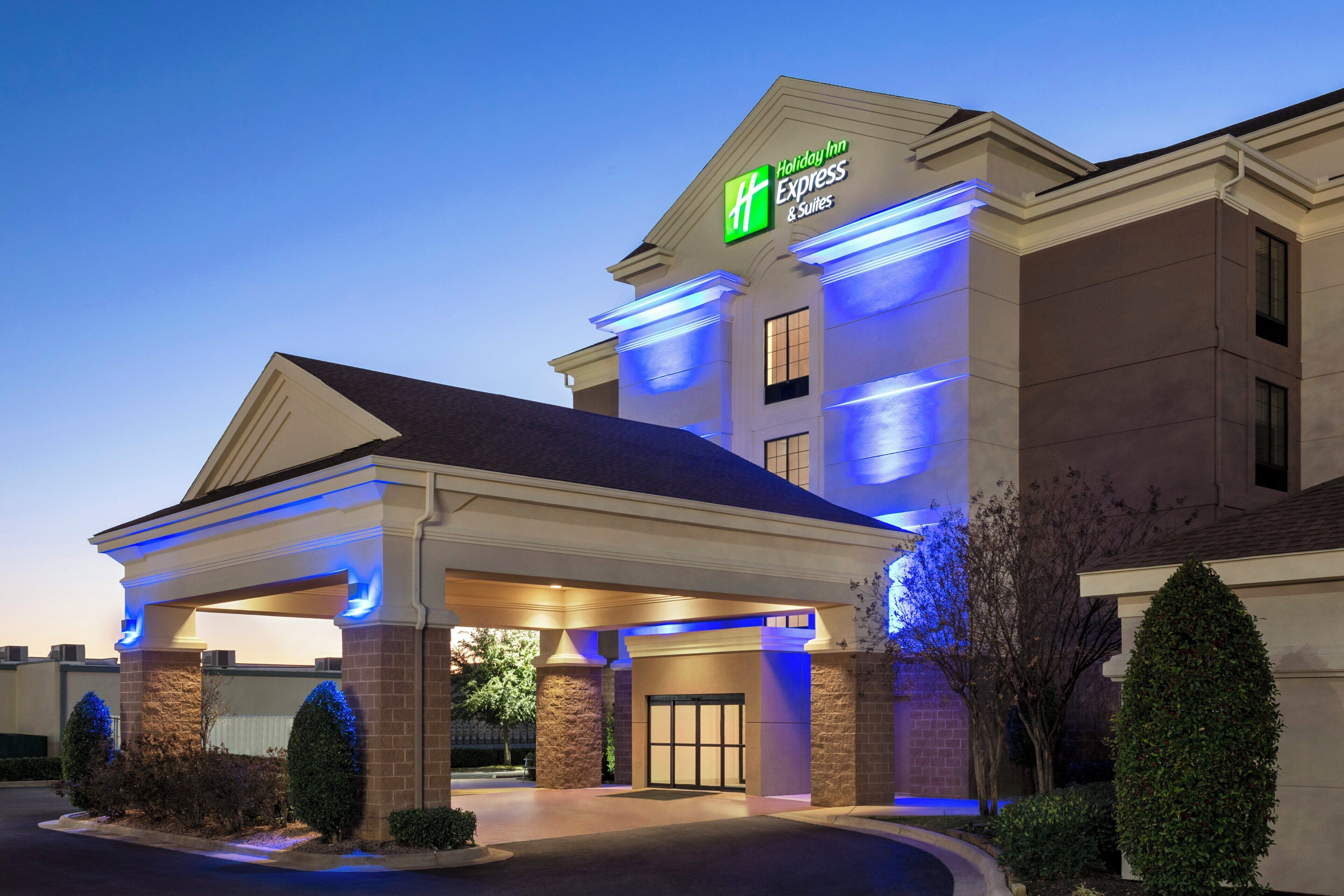 Edificio de Holiday Inn Express & Suites con entrada cubierta y cielo despejado.