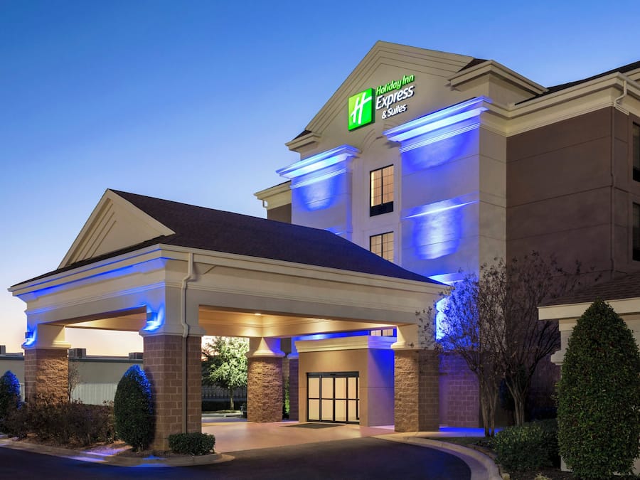 A Holiday Inn Express & Suites building with a covered entrance and a clear sky.