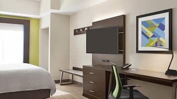 A hotel room with a bed, a desk with a chair, a flat-screen TV, a telephone, and a framed abstract painting on the wall.