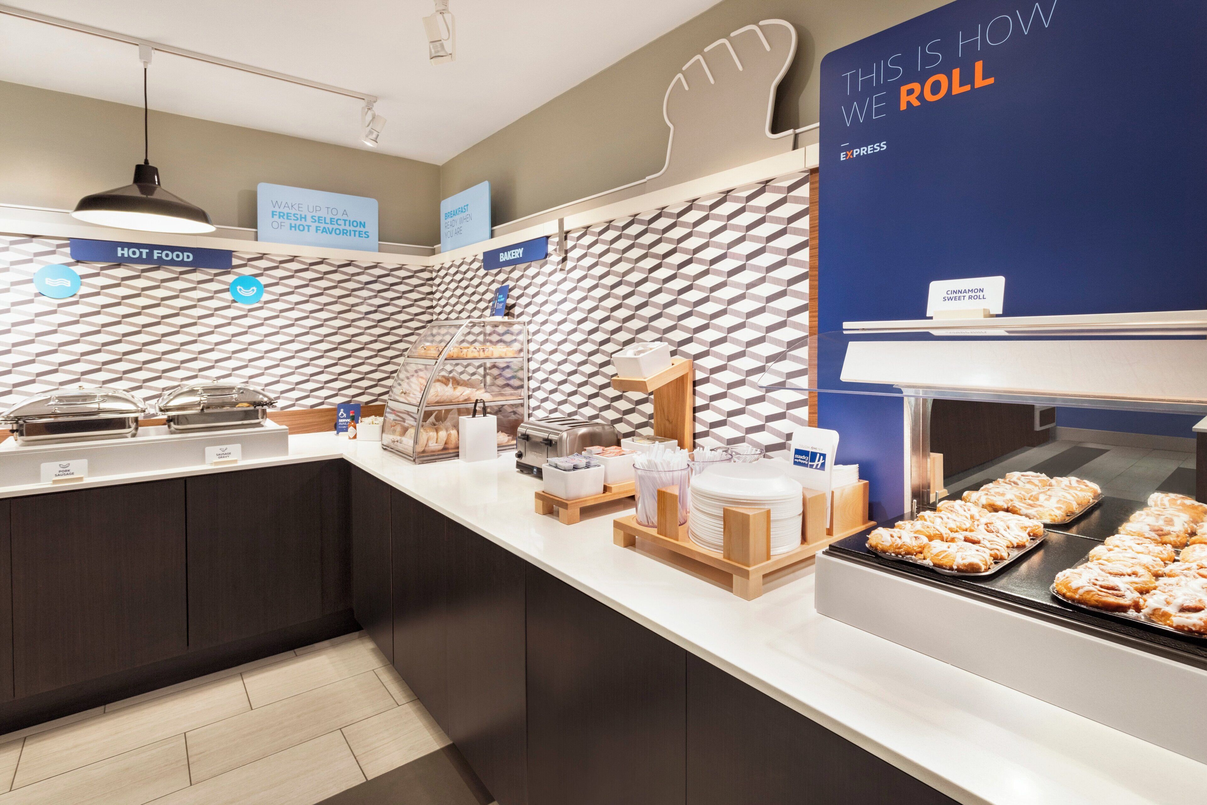 Zona de desayuno tipo buffet con diversas opciones de comida, incluyendo una presentación de rollitos de canela.