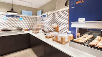 Zona de desayuno tipo buffet con diversas opciones de comida, incluyendo una presentación de rollitos de canela.
