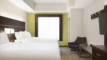 A hotel room with two beds, a desk, a chair, and a large window.