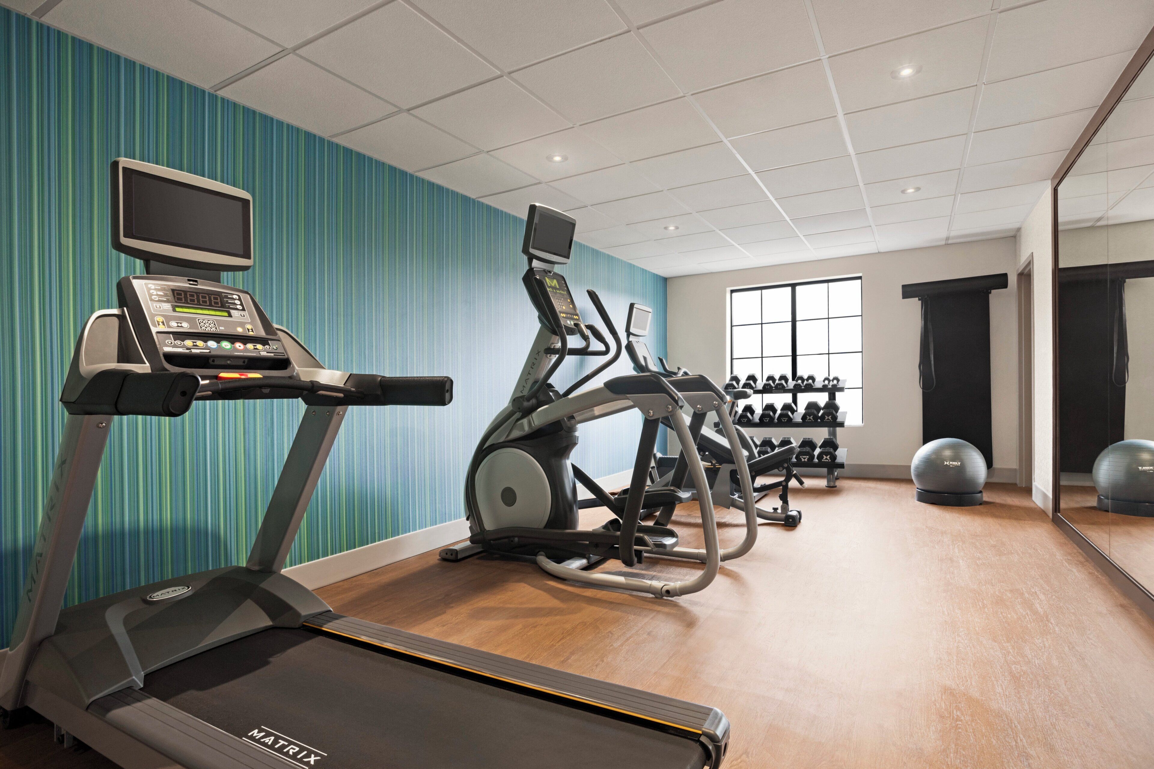 A gym with treadmills, an elliptical, and free weights.