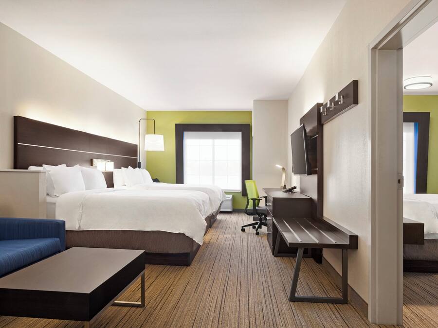 A hotel room with a bed, a desk, a chair, a sofa, and a television.