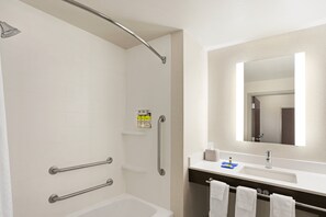 A modern bathroom with a bathtub, a shower with a glass door, a vanity with a mirror, and a towel rack.