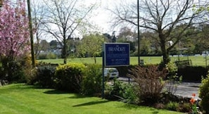 A sign for a hotel named "Branice" with a view of a park and a body of water in the background. - The Brandize Guest House (Torquay)