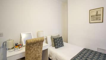 A hotel room with a bed, a desk with a chair, a coffee maker, and a framed picture on the wall.