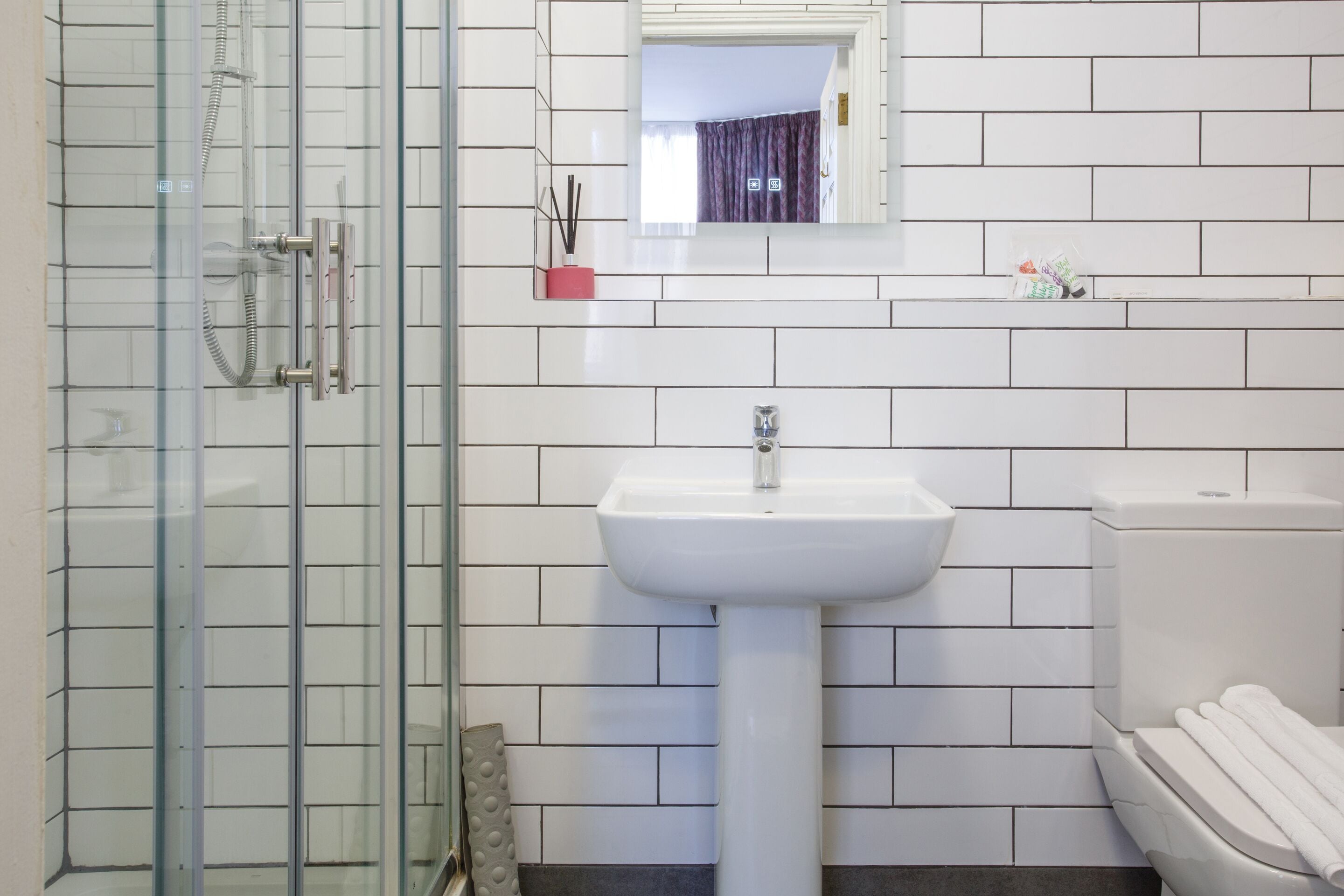 Une salle de bain avec une douche à parois de verre, un lavabo blanc et des toilettes.