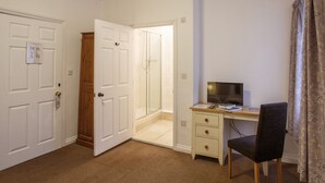 A room with a desk, chair, and a door leading to a shower area. - The Buttery Hotel (Oxford)