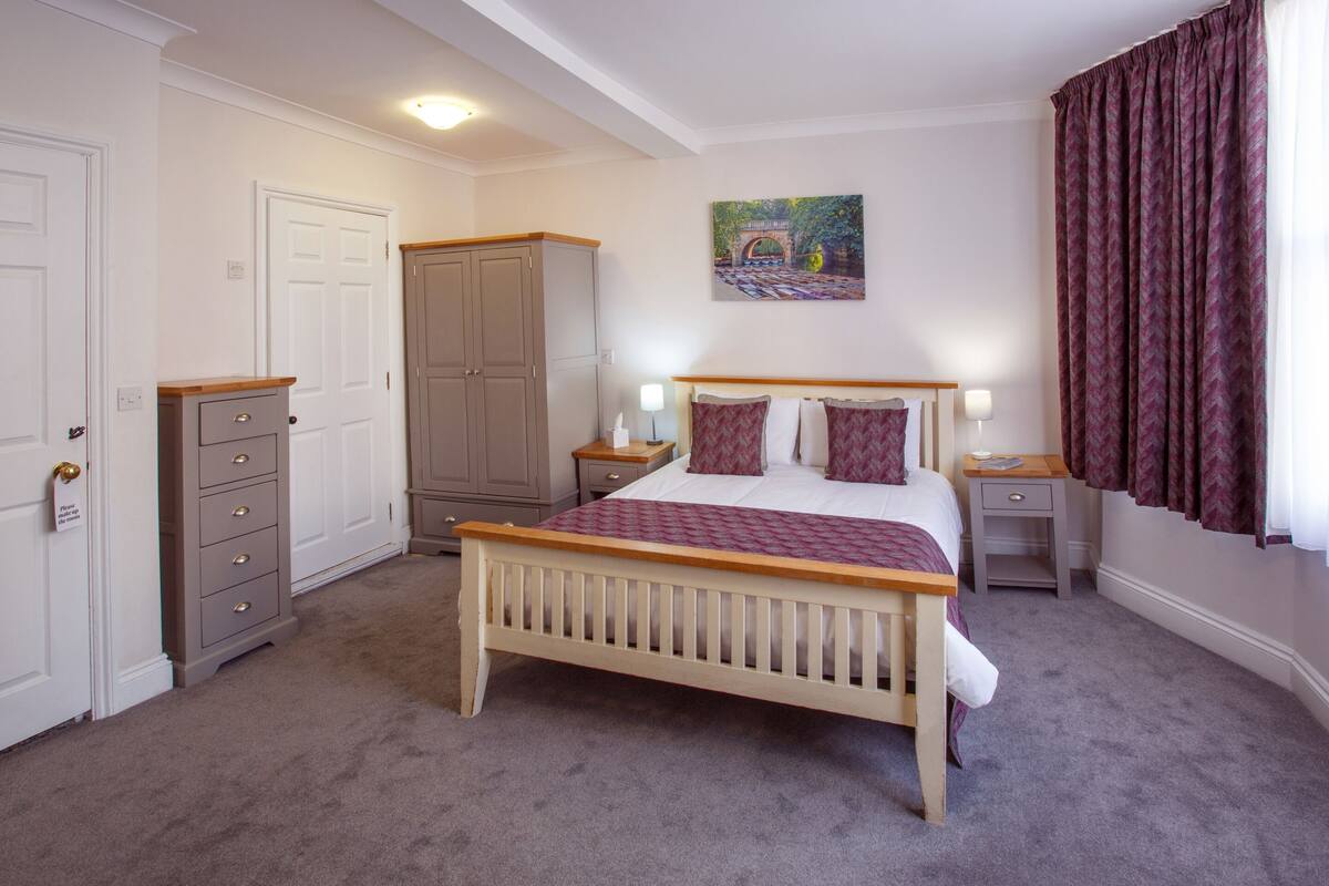 A bedroom with a wooden bed, a nightstand, a dresser, and a wardrobe.