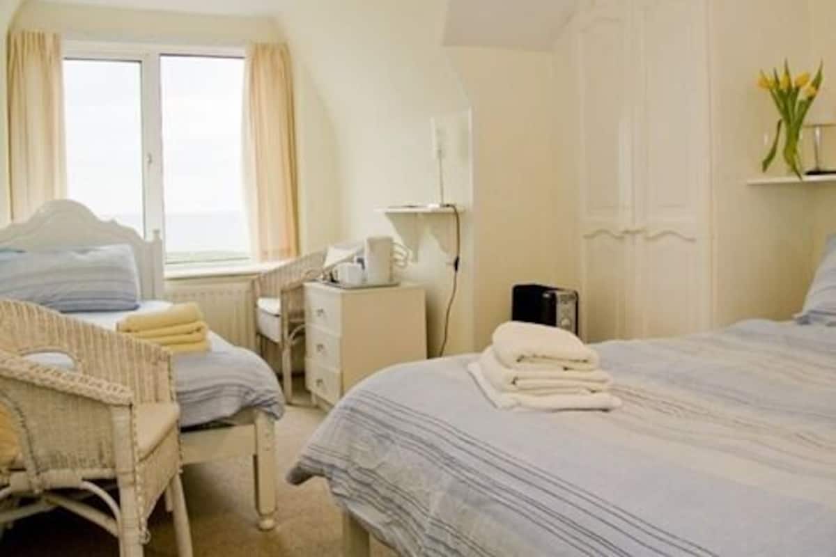 Una habitación de hotel con cama, una silla, un escritorio y una ventana.