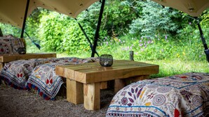 A tented area with wooden tables and benches, surrounded by lush greenery and flowers. - The Filly Inn (Brockenhurst)