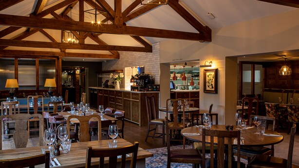 A restaurant with wooden beams, tables set for dining, and a bar area. - The Filly Inn (Brockenhurst)