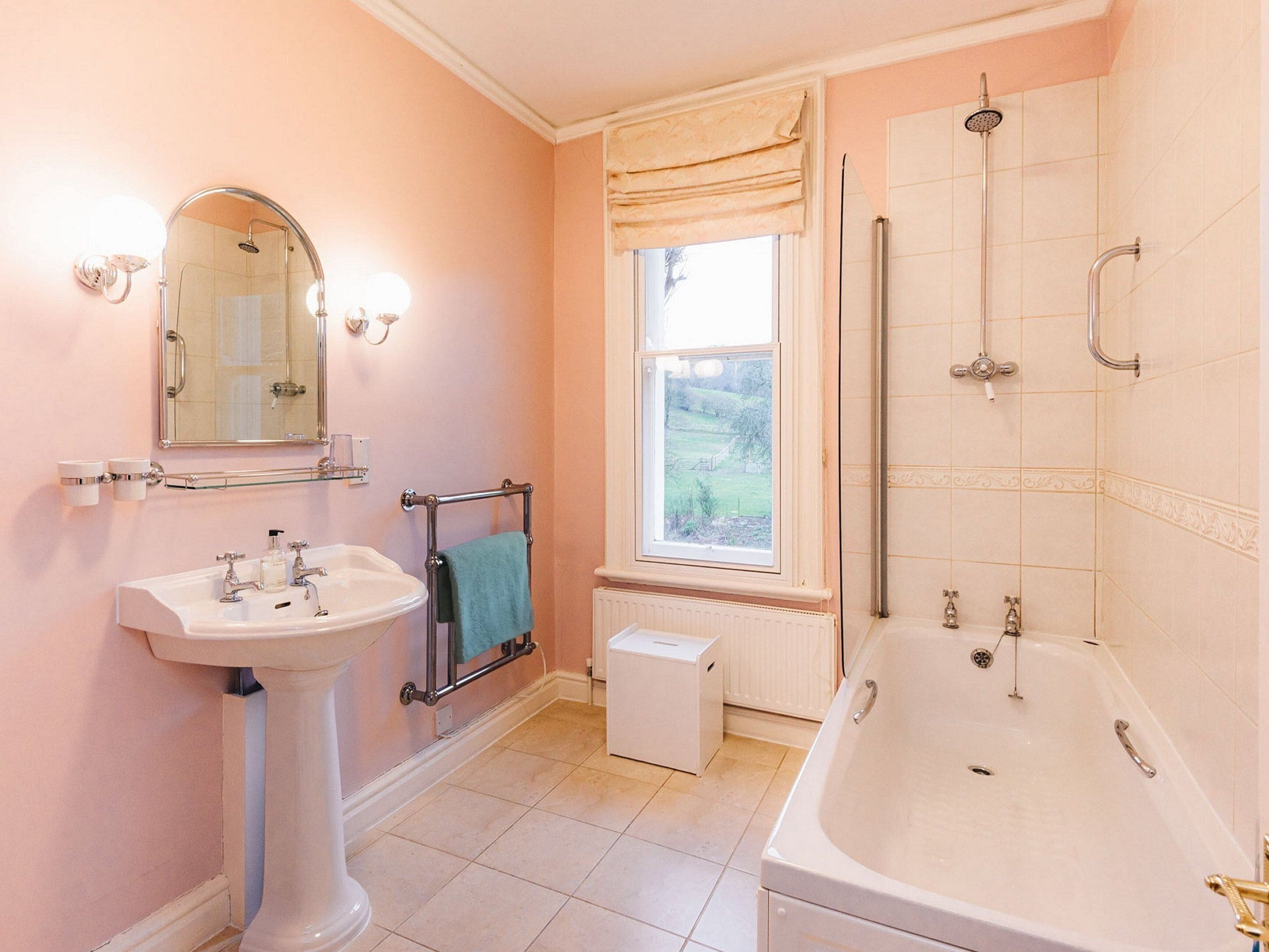 A bathroom with a pedestal sink, a bathtub, a shower, and a window.