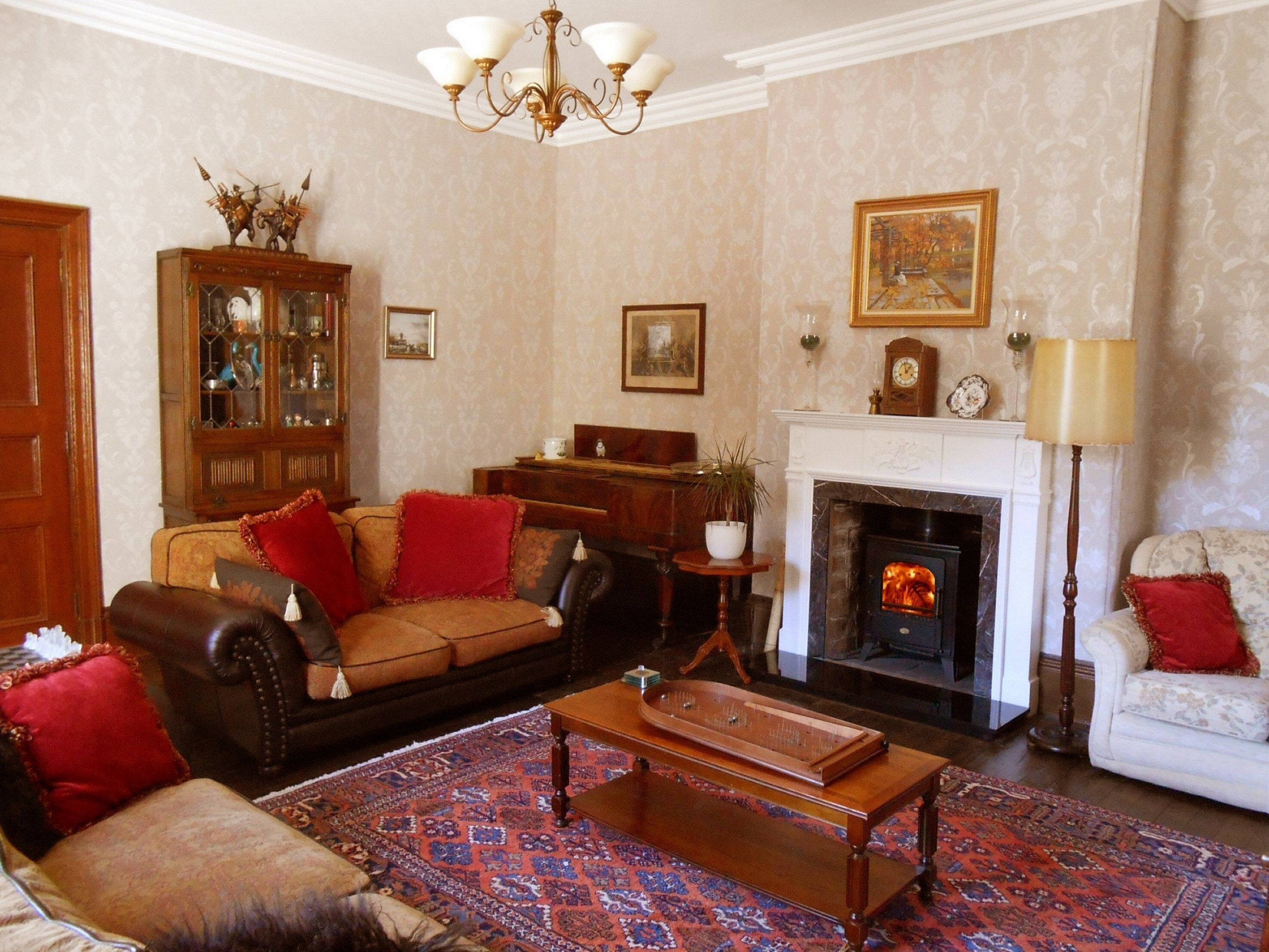 A traditional living room with a fireplace, a sofa, a cabinet, and a chandelier.