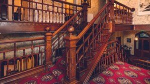 A grand staircase with ornate woodwork and a red patterned carpet. - The Forest Country House B&B (Newtown)